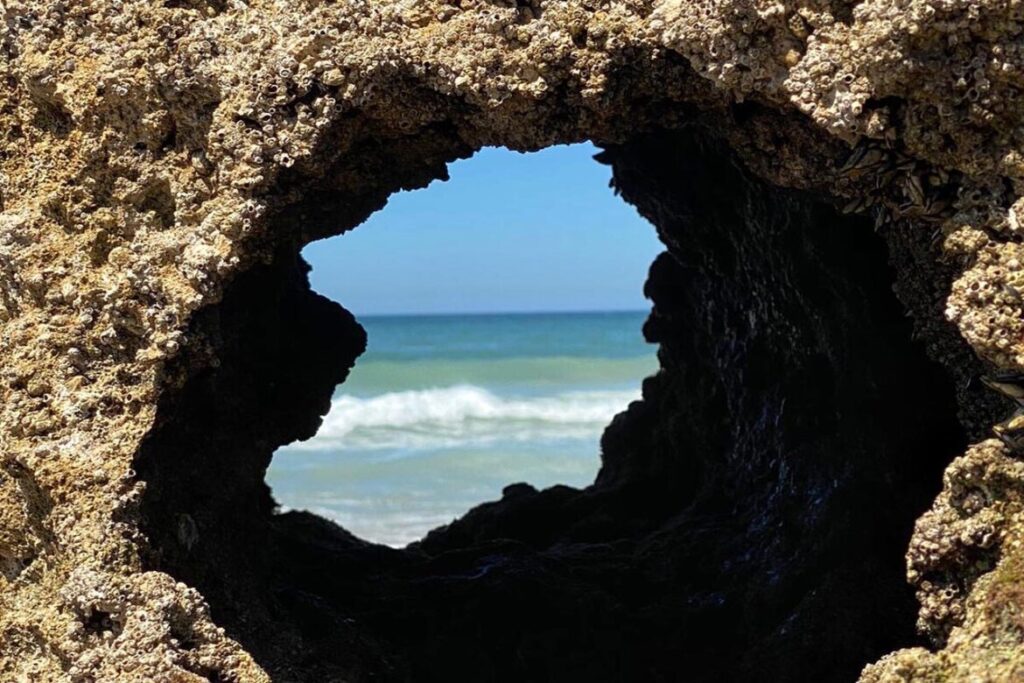 Cala de Roche sheltered cove beneath reddish cliffs in Conil de la Frontera, Cádiz
