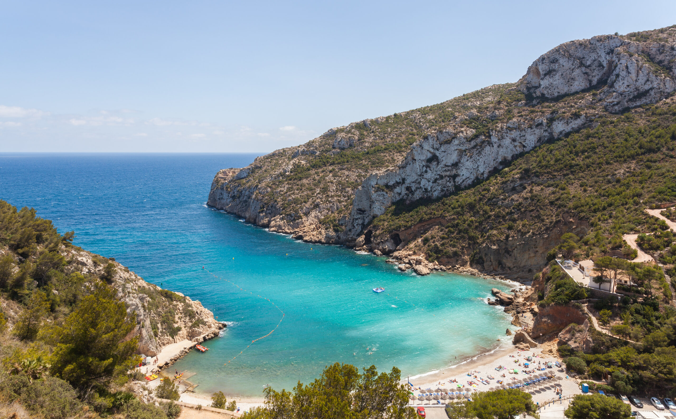 Cala de la Granadella in Jávea, Alicante: a sheltered pebble cove enclosed by pine-covered cliffs with turquoise water