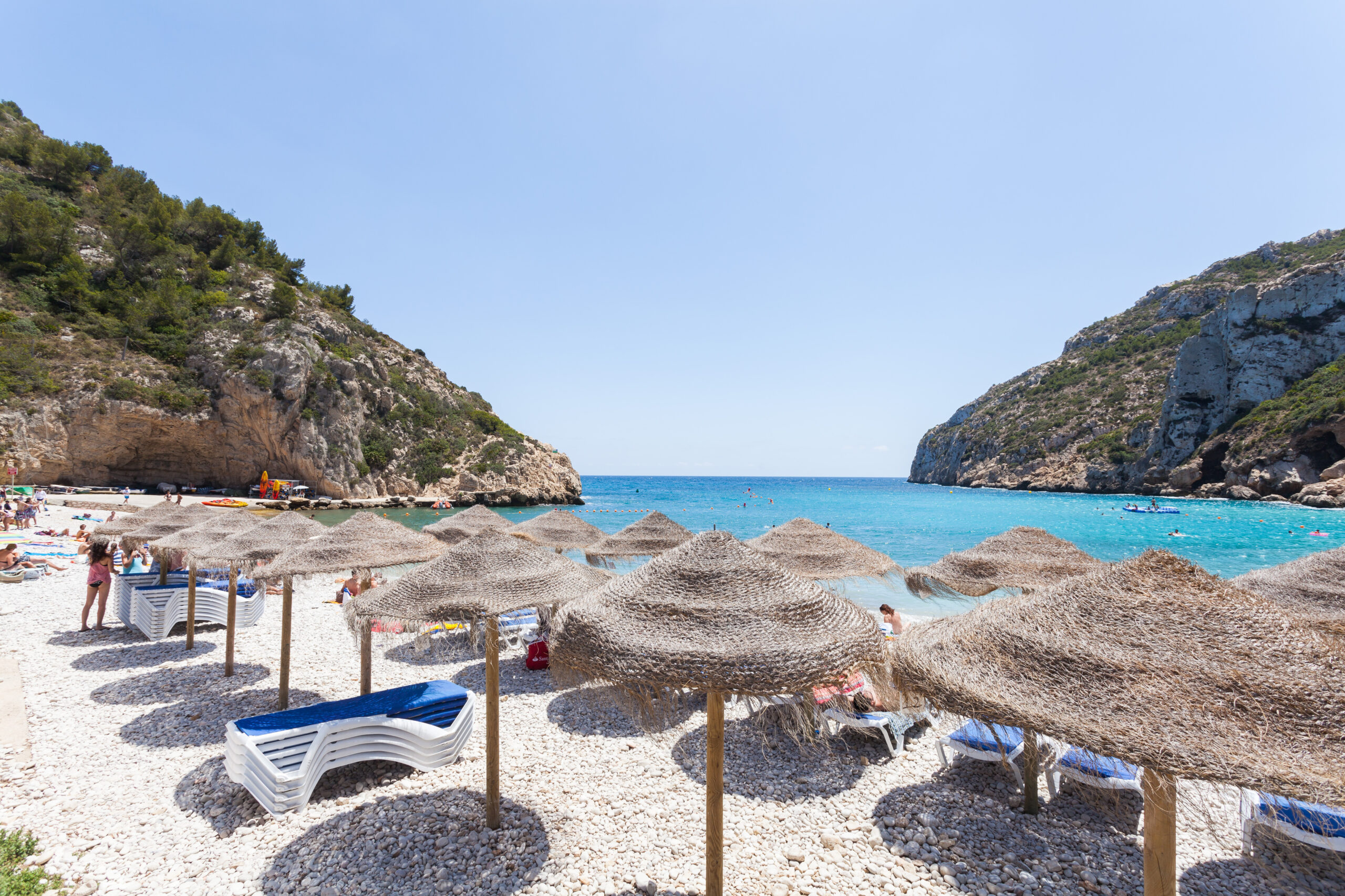 Turquoise water and pebble shoreline at Cala de la Granadella, Jávea, enclosed by rocky headlands